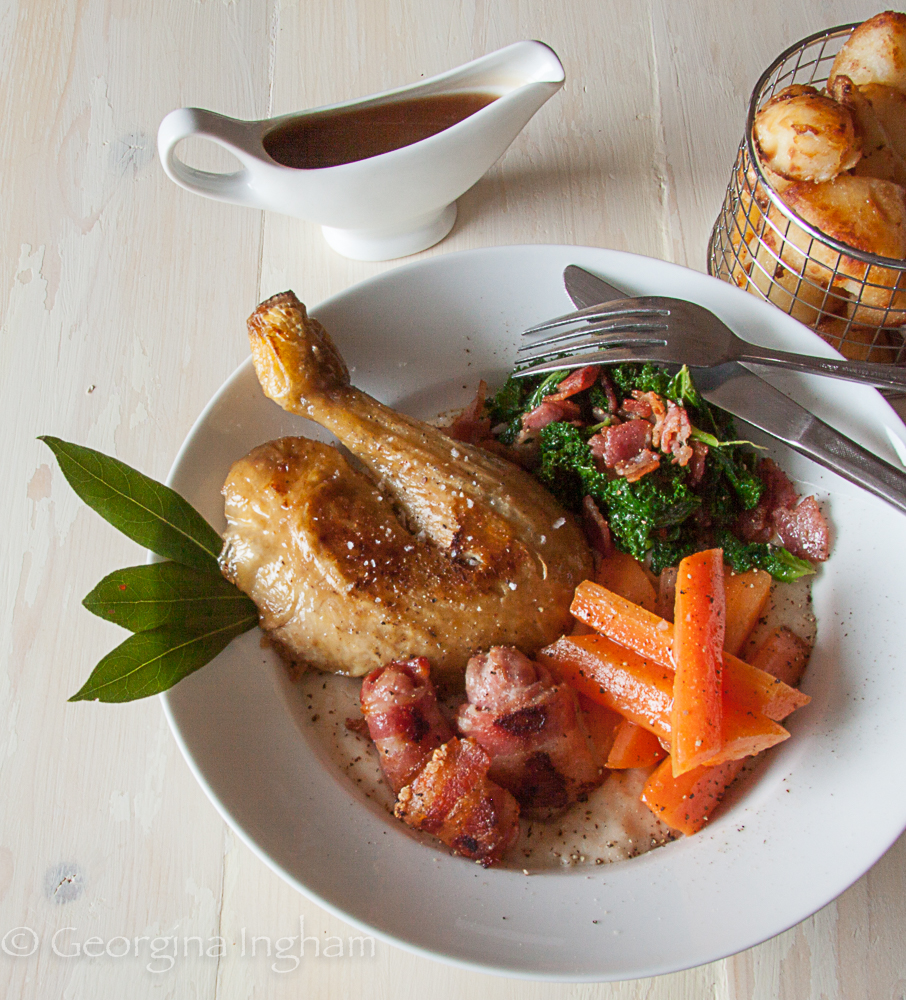 oast chicken served with carrots, kale and bacon, roast potatoes and gravy — a classic British comfort food dinner flavoured with herbs.